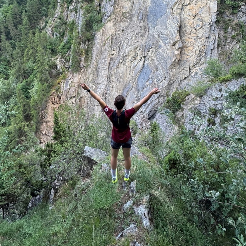Trail en montagne, bras ouverts face à la falaise